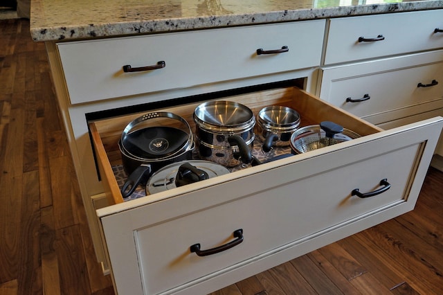 details with white cabinetry, dark wood finished floors, light stone counters, and stovetop