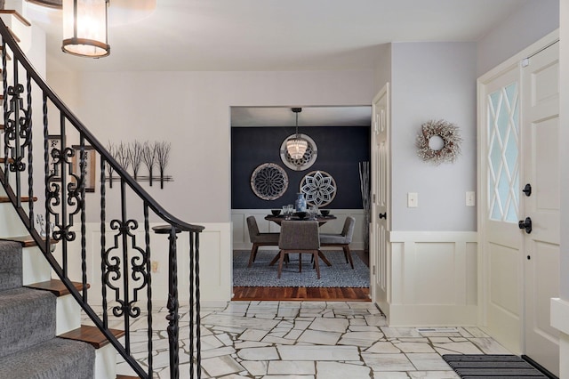 foyer entrance with a wainscoted wall, stairway, and a decorative wall