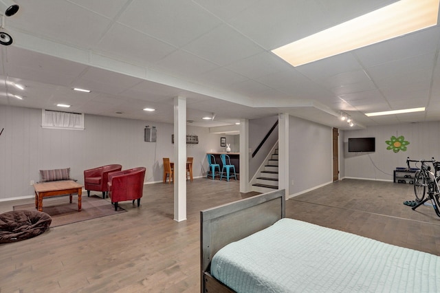 interior space featuring stairs, a paneled ceiling, baseboards, and wood finished floors