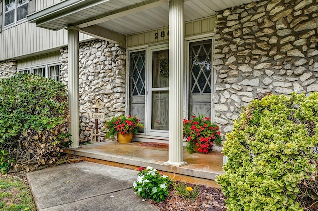 view of exterior entry featuring board and batten siding and stone siding