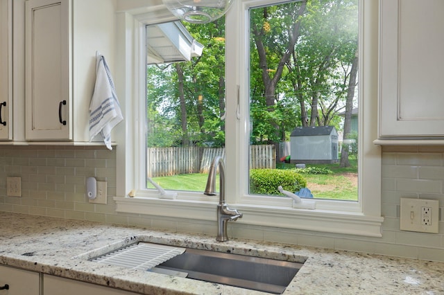 kitchen with light stone counters, white cabinets, and a sink