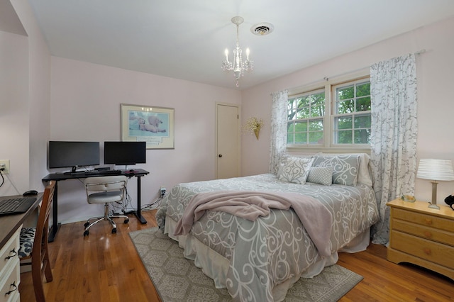 bedroom featuring wood finished floors, visible vents, and a notable chandelier