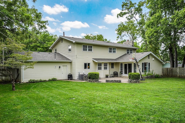 back of property featuring a lawn, a chimney, fence, and central air condition unit