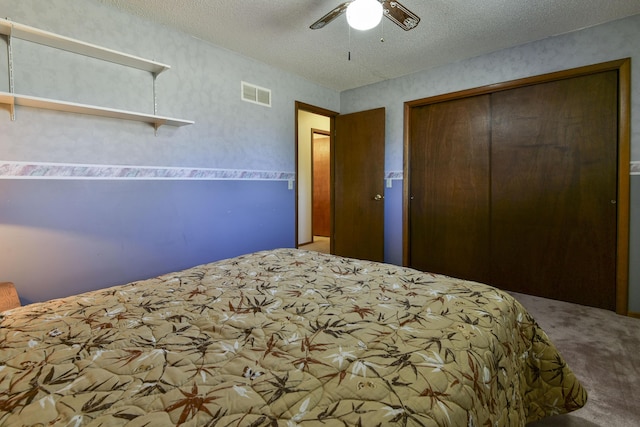 carpeted bedroom with a ceiling fan, a textured ceiling, visible vents, and a closet