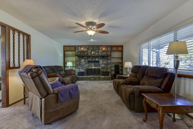 carpeted living area with ceiling fan, a fireplace, baseboards, and a textured ceiling