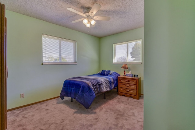 bedroom featuring light carpet, multiple windows, and a textured ceiling