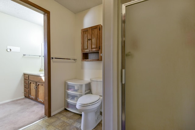 full bath featuring toilet, a stall shower, vanity, and baseboards