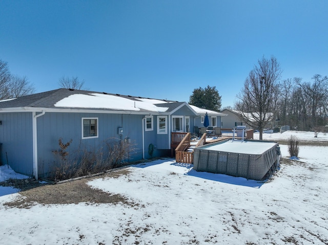 snow covered back of property with a deck