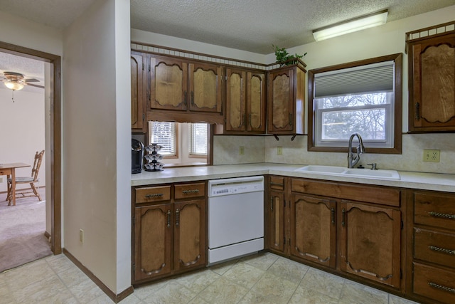 kitchen with plenty of natural light, light countertops, white dishwasher, and a sink