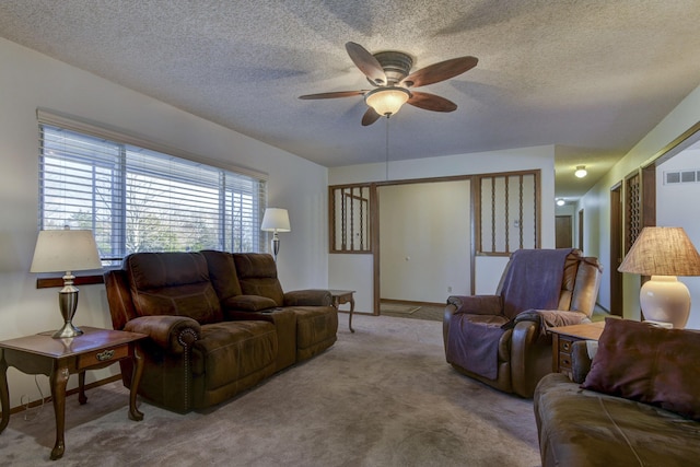 living room with ceiling fan, a textured ceiling, light carpet, visible vents, and baseboards