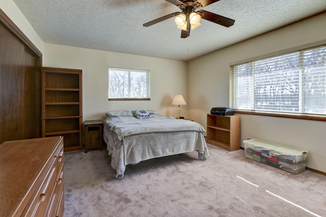 bedroom featuring a ceiling fan, a closet, light colored carpet, and a textured ceiling