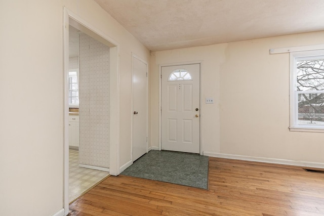 entrance foyer featuring light wood-style flooring, visible vents, and baseboards