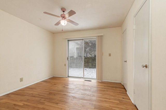 spare room featuring light wood finished floors, baseboards, visible vents, and a ceiling fan