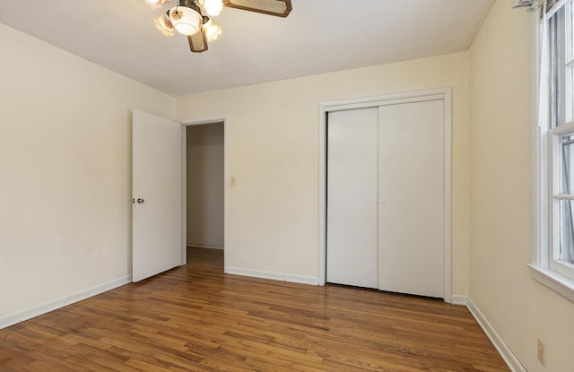 unfurnished bedroom featuring a ceiling fan, a closet, baseboards, and wood finished floors