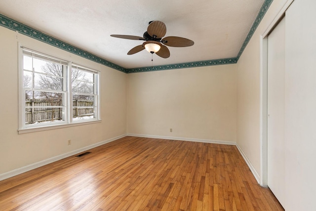 empty room featuring visible vents, a ceiling fan, light wood-style flooring, and baseboards