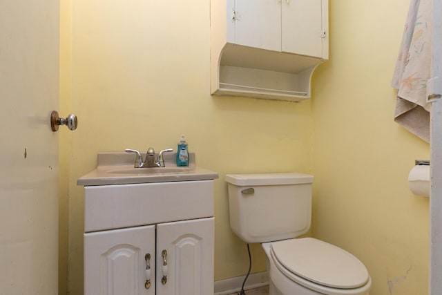 bathroom with toilet, baseboards, and vanity