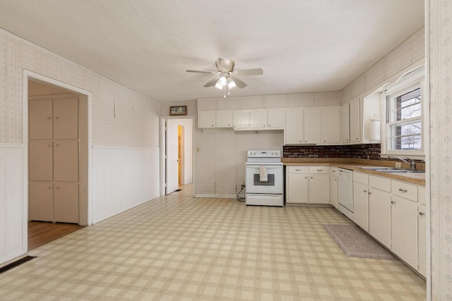 kitchen with white appliances, light floors, a sink, and wainscoting