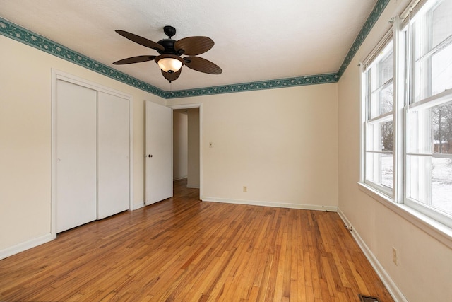 unfurnished bedroom with light wood-style floors, multiple windows, and baseboards