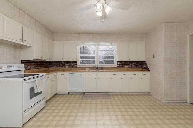 kitchen featuring white appliances, a sink, and wallpapered walls