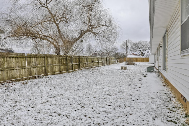 yard layered in snow featuring cooling unit and a fenced backyard