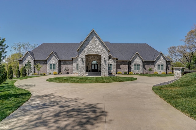 french country home with curved driveway and a front lawn