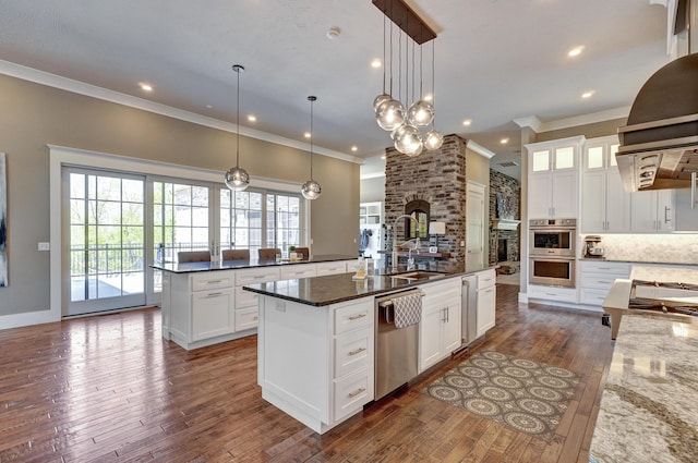 kitchen with a spacious island, dark wood finished floors, ornamental molding, a sink, and appliances with stainless steel finishes