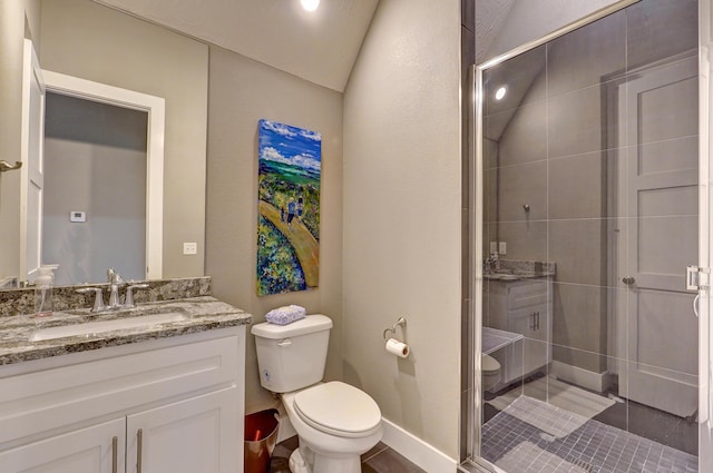 bathroom with baseboards, toilet, lofted ceiling, a stall shower, and vanity