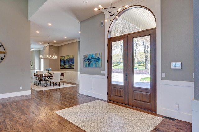 foyer entrance featuring visible vents, dark wood-type flooring, french doors, a towering ceiling, and a notable chandelier