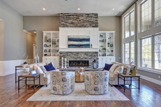 living room with visible vents, hardwood / wood-style floors, recessed lighting, wainscoting, and a brick fireplace