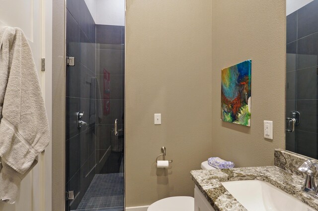 bathroom with a shower stall, vanity, and toilet