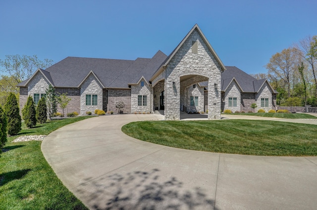 french country inspired facade with a front yard and driveway