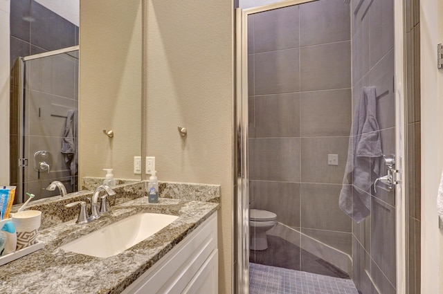 full bathroom featuring toilet, a stall shower, and vanity