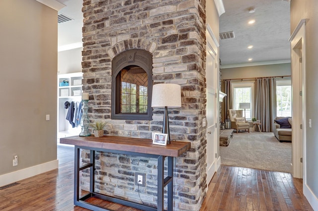 interior space featuring hardwood / wood-style floors, visible vents, and ornamental molding