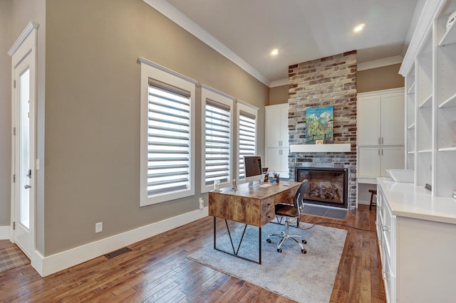 office area featuring visible vents, wood-type flooring, a large fireplace, crown molding, and baseboards