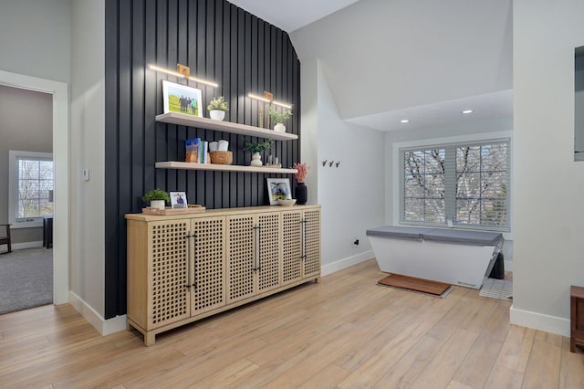 interior space featuring recessed lighting, wood finished floors, baseboards, and a towering ceiling