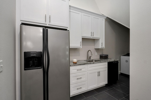 kitchen with dark tile patterned flooring, a sink, black dishwasher, white cabinetry, and stainless steel fridge