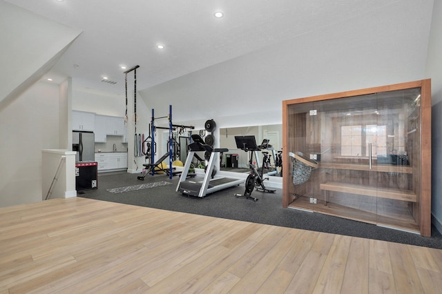 exercise room featuring visible vents, recessed lighting, lofted ceiling, and wood finished floors