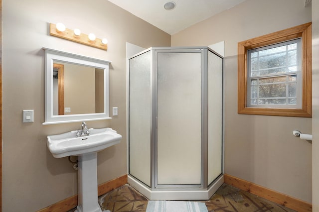 full bath with lofted ceiling, a shower stall, and baseboards