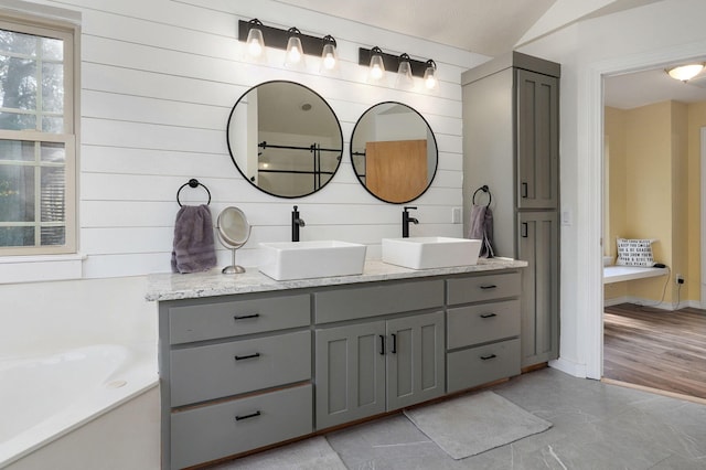 ensuite bathroom with double vanity, ensuite bath, a sink, and a bathtub