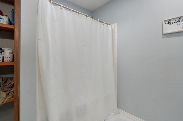 full bathroom featuring marble finish floor and baseboards