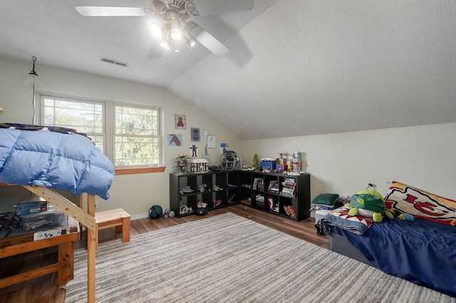 bedroom with visible vents, ceiling fan, vaulted ceiling, a textured ceiling, and wood finished floors