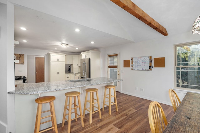 kitchen with freestanding refrigerator, white cabinets, a peninsula, and a kitchen bar