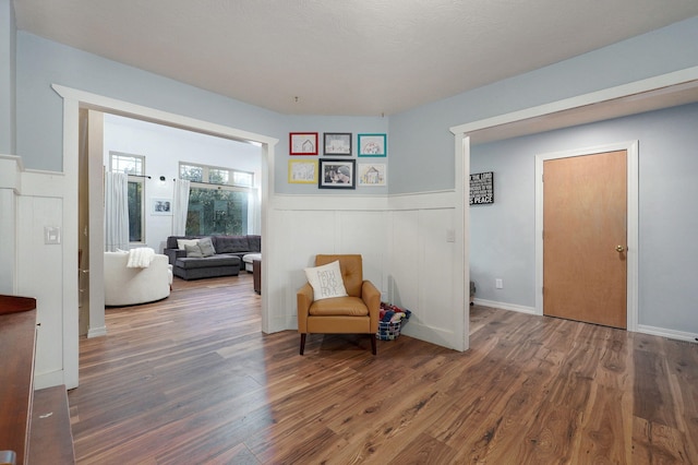 sitting room with a wainscoted wall and wood finished floors