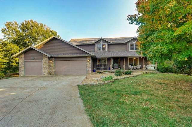 view of front facade with a porch, a front yard, driveway, and an attached garage