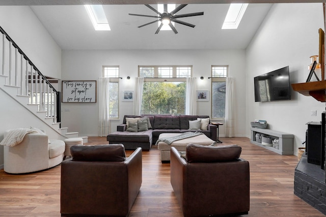 living room featuring a skylight, stairs, and wood finished floors