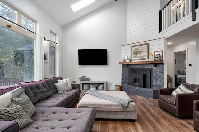 living room featuring high vaulted ceiling, a skylight, and wood finished floors