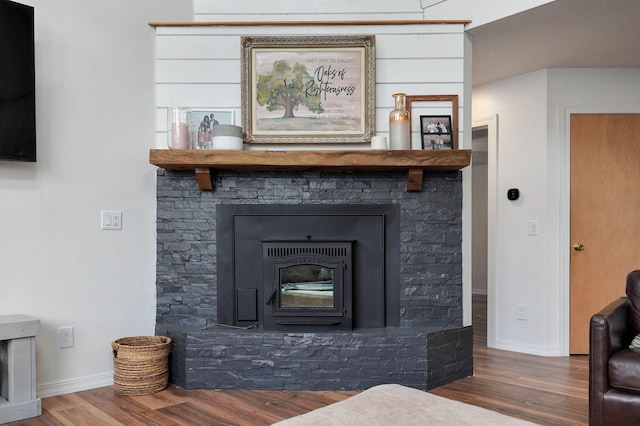 living room with a wood stove, baseboards, and wood finished floors