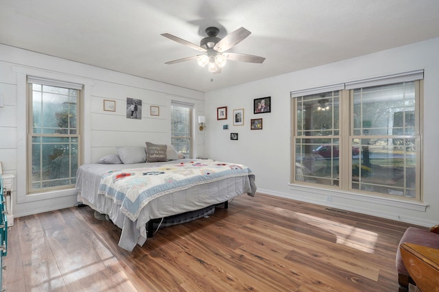 bedroom featuring visible vents, ceiling fan, baseboards, and wood finished floors