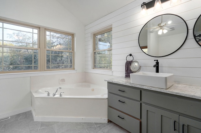 bathroom featuring marble finish floor, lofted ceiling, vanity, baseboards, and a bath