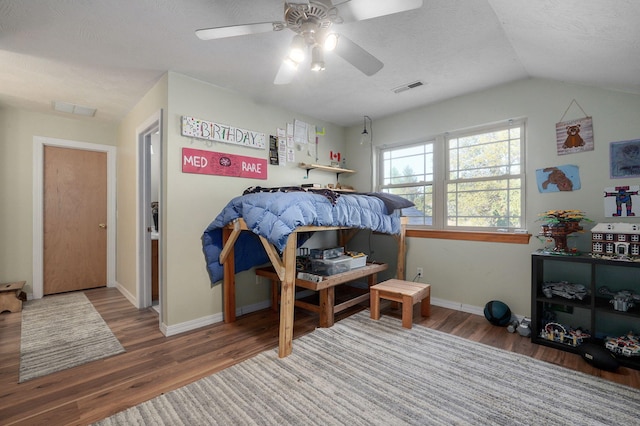 bedroom featuring baseboards, visible vents, a ceiling fan, wood finished floors, and vaulted ceiling